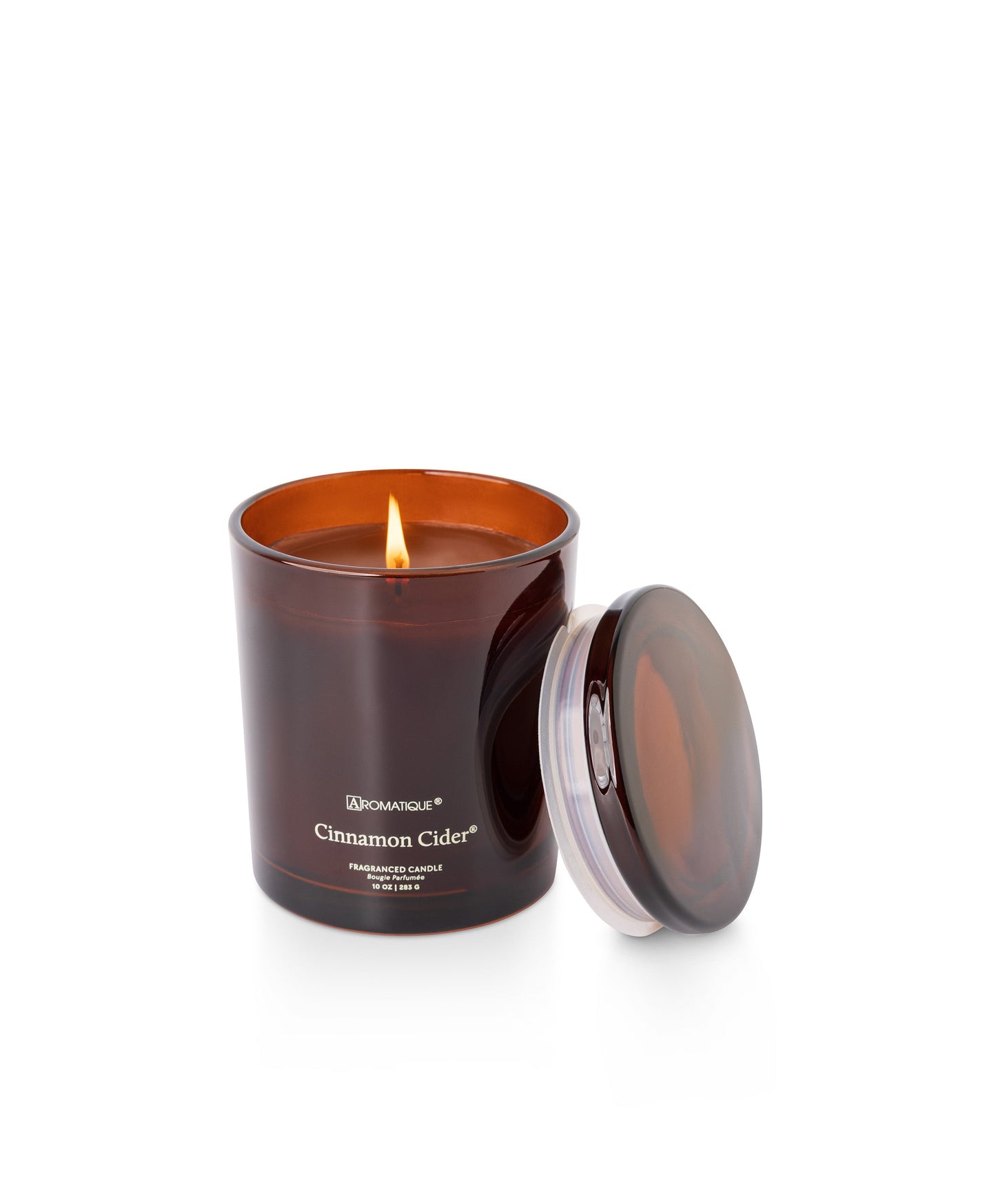 Candle in an amber jar with a lit wick on a white background